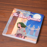 Flat-lay photo of The Three Spinners picture book on a table