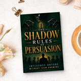 The Shadow Rules of Persuasion - paperback beside writing materials